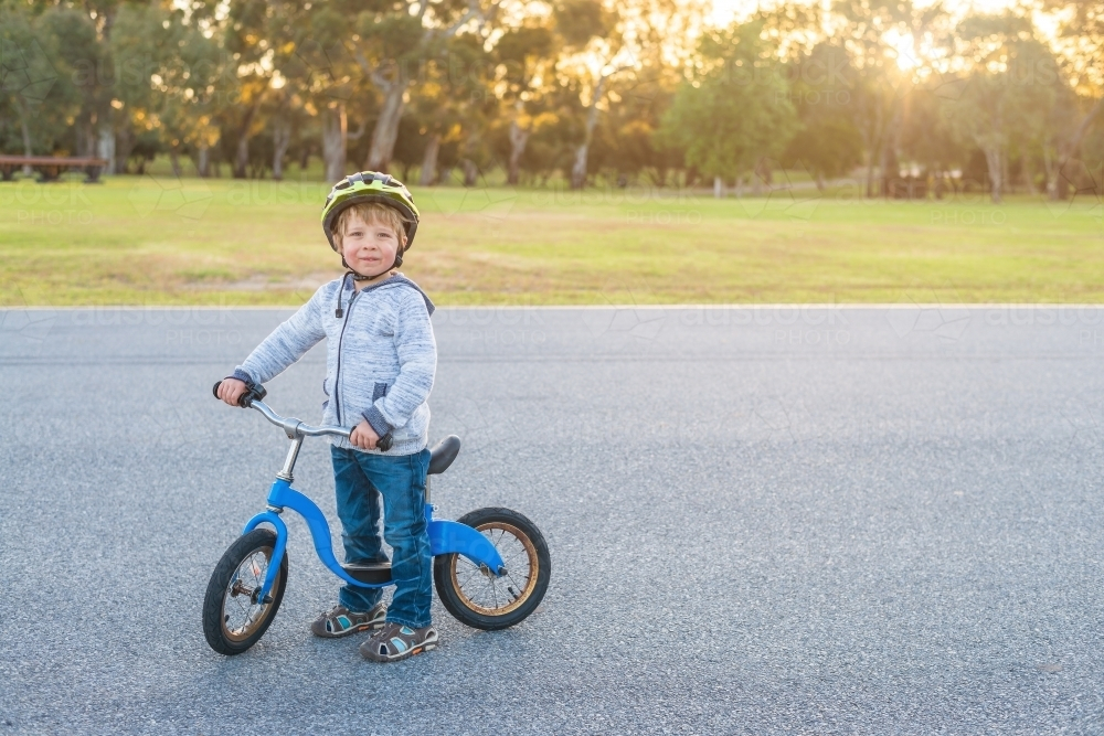 Boy riding his balance bike at sunset in Adelaide Park Lands, South Australia - Australian Stock Image