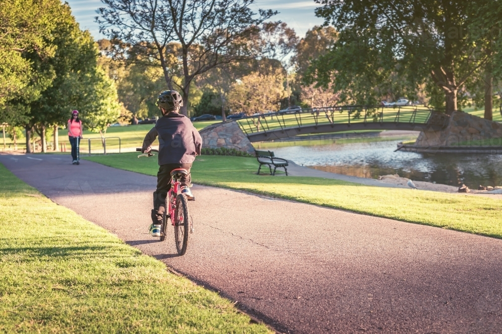 Boy riding his bicycle along the bike lane in Adelaide Park Lands on a day - Australian Stock Image