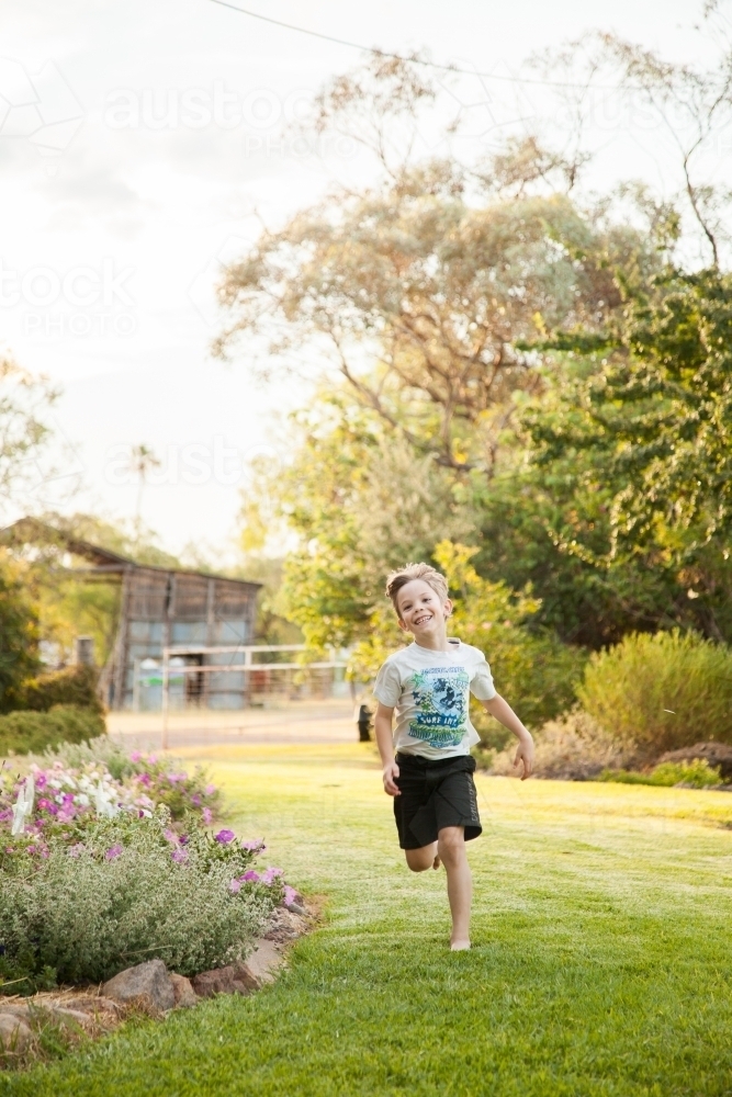 Image of Boy running in backyard Austockphoto