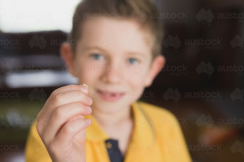 Boy showing tooth that has fallen out to camera - Australian Stock Image