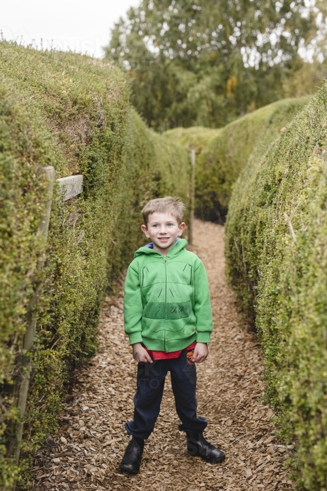 Boy standing in a maze smiling - Australian Stock Image