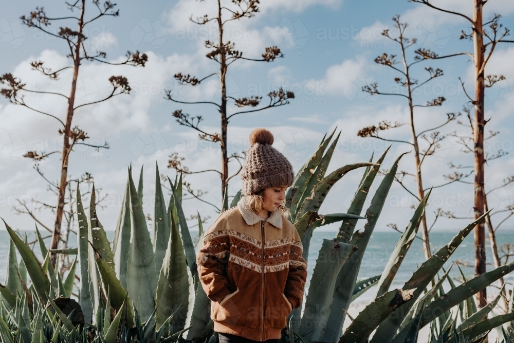 Boy standing in front of cactus' with the ocean behind - Australian Stock Image