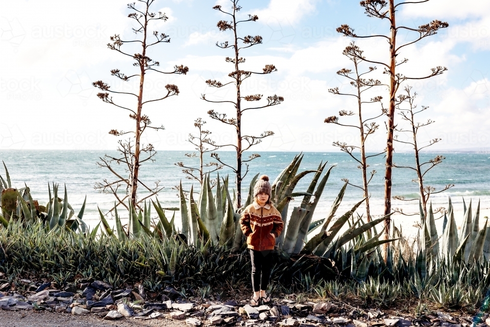 Boy standing in front of cactuses by the ocean - Australian Stock Image