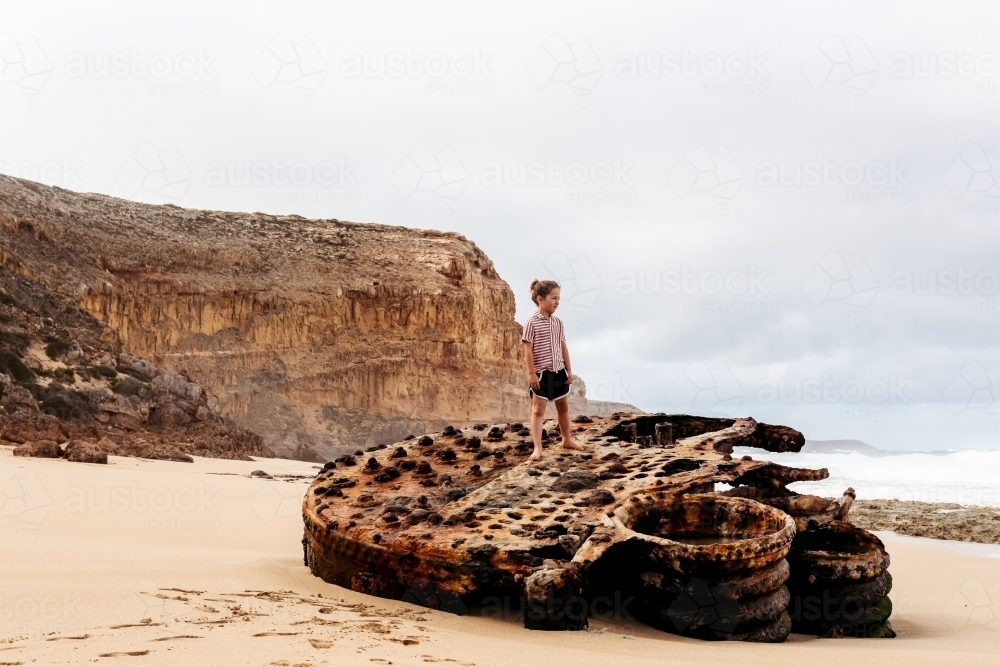 Boy standing on top of ship wreck - Australian Stock Image