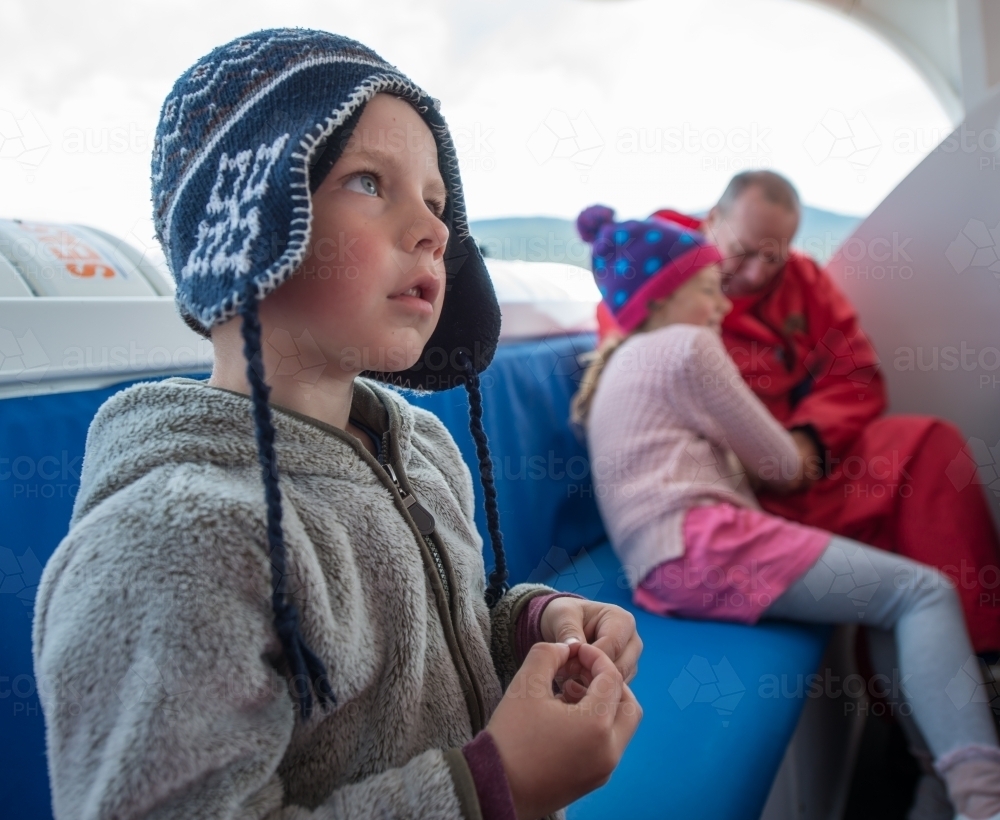 Boy travelling on a boat in cold weather - Australian Stock Image