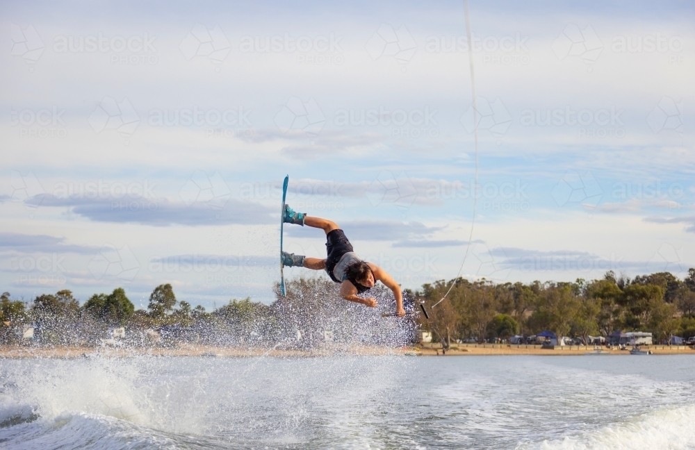 Boy upside down in the air doing tricks on wake board - Australian Stock Image