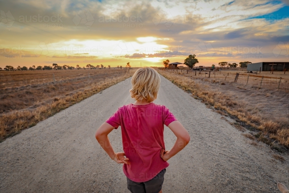Boy walking along country road at sunset - Australian Stock Image