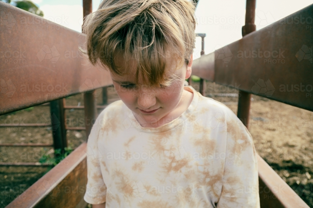 Boy walking through cattle yards on farm in the country - Australian Stock Image