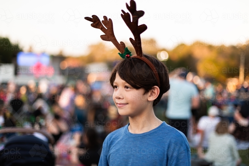 boy wearing reindeer antlers at the carols - Australian Stock Image