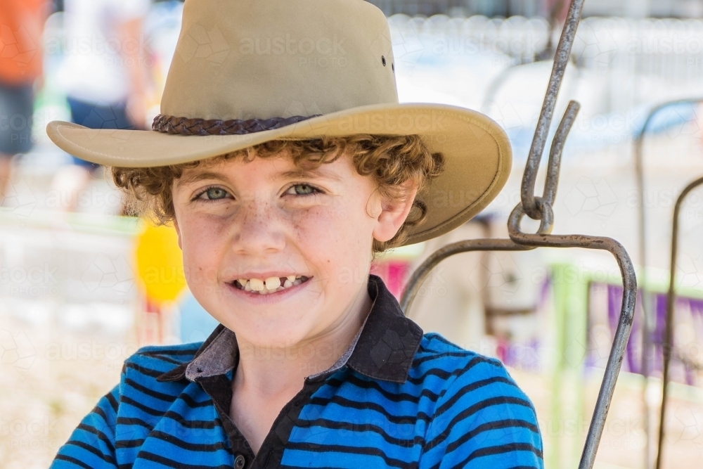 Boy with curly hair smiling wearing akubra hat - Australian Stock Image