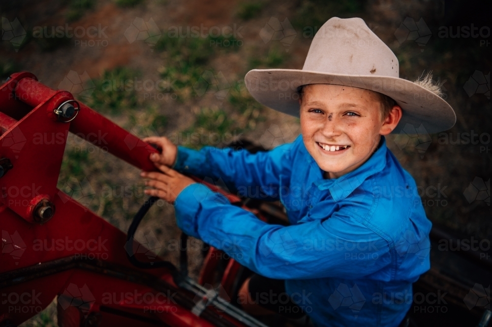 Boy with farming equipment smiling at camera - Australian Stock Image