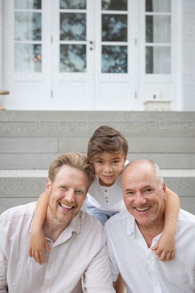Boy with father and grandfather sitting on outdoor stairs - Australian Stock Image