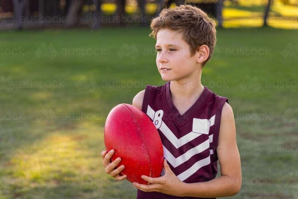 boy with football wearing sleeveless football jersey - Australian Stock Image