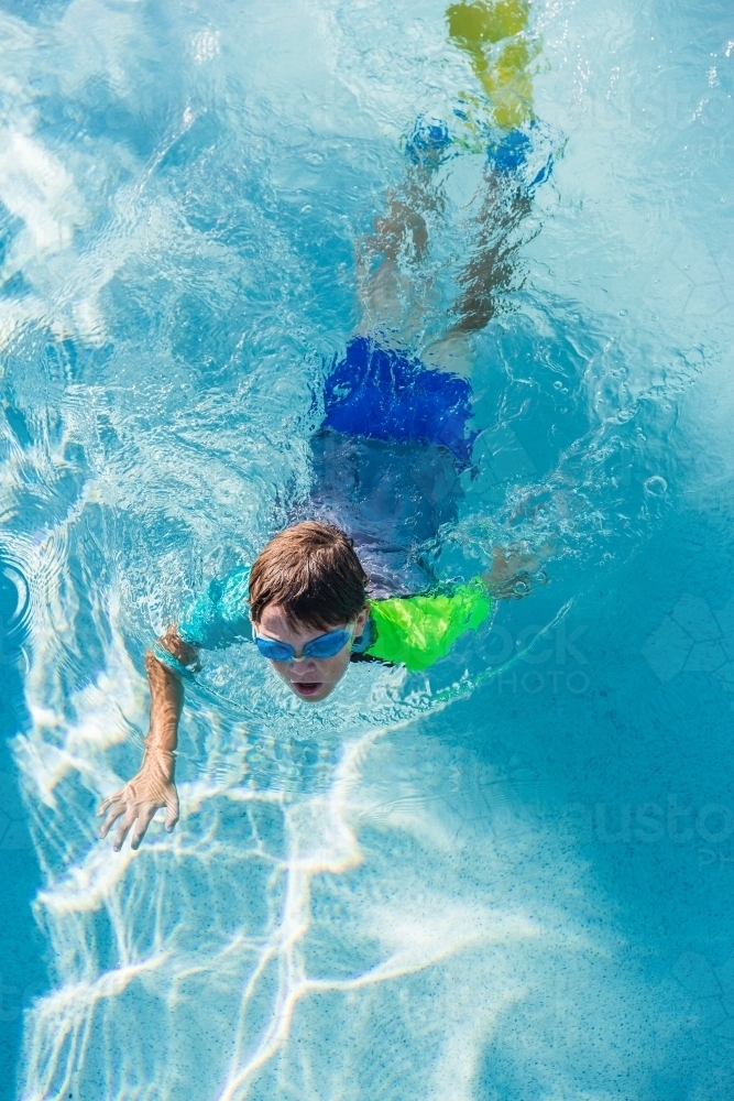 Boy with goggles and flippers swimming in pool from above - Australian Stock Image