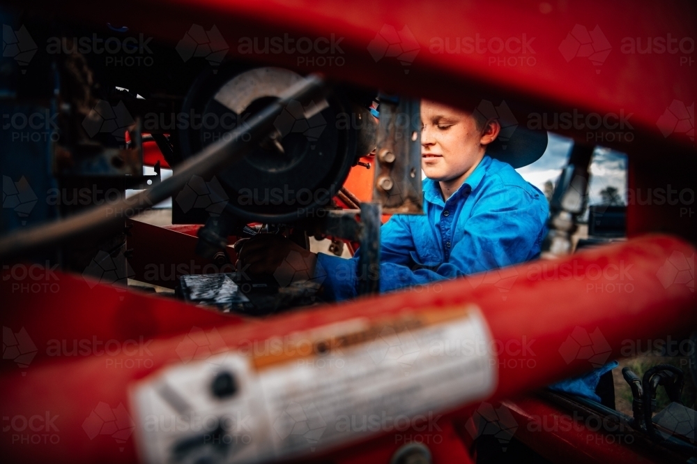 Boy working  behind farming equipment - Australian Stock Image