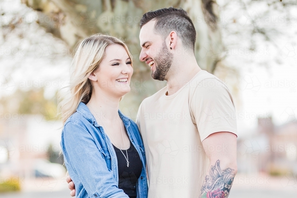 Boyfriend and girlfriend in arms laughing at each other - Australian Stock Image