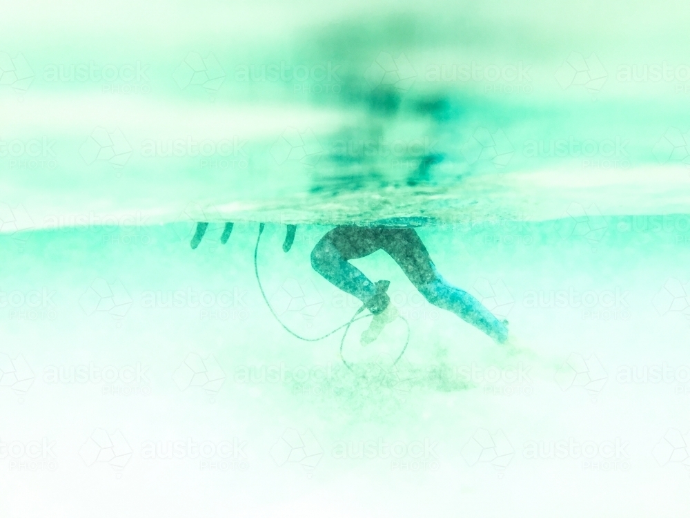 Boys legs underwater pushing surfboard - Australian Stock Image