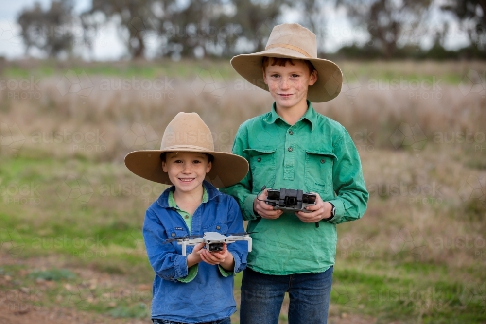 Boys using a drone in the paddock on a farm - Australian Stock Image