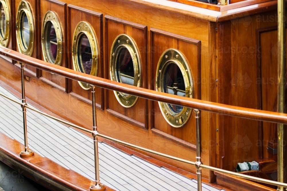 Brass portholes and deck on wooden boat - Australian Stock Image