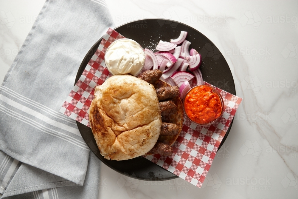 Bread roll with grilled meat, dipping sauce and red onions on the side - Australian Stock Image