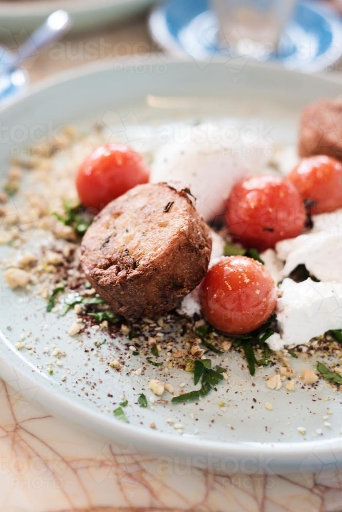 breakfast of poached eggs with roasted cherry tomato, potato rosti, feta and nut crumb with herbs - Australian Stock Image