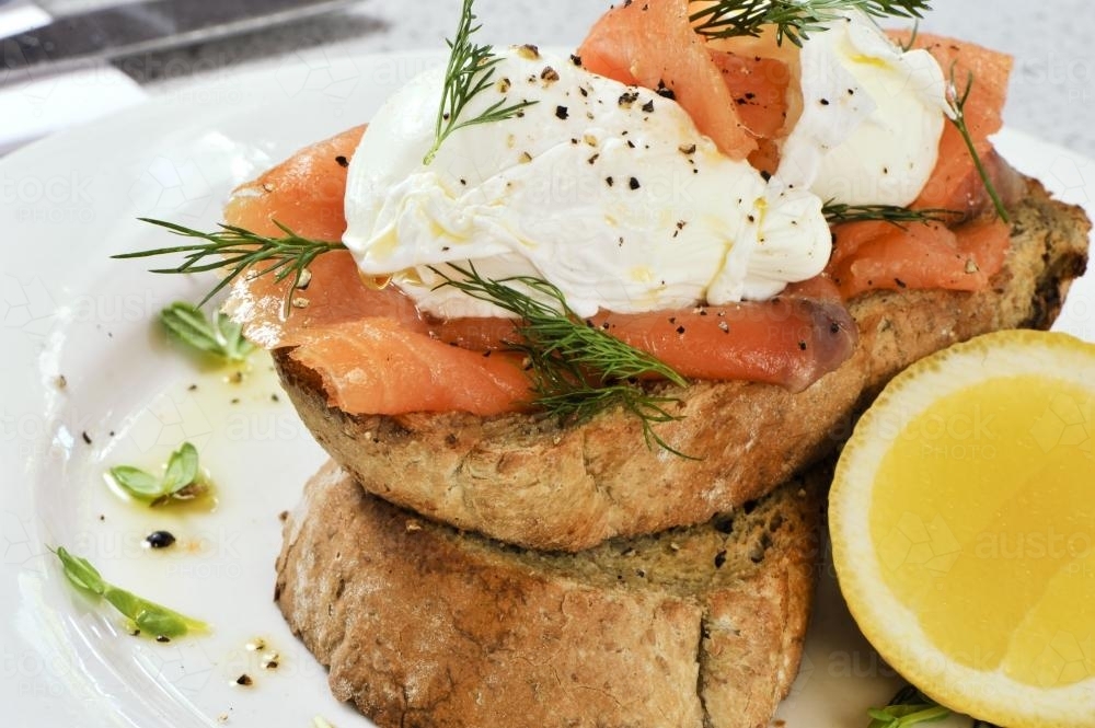 Breakfast of smoked salmon, poached eggs and bread - Australian Stock Image