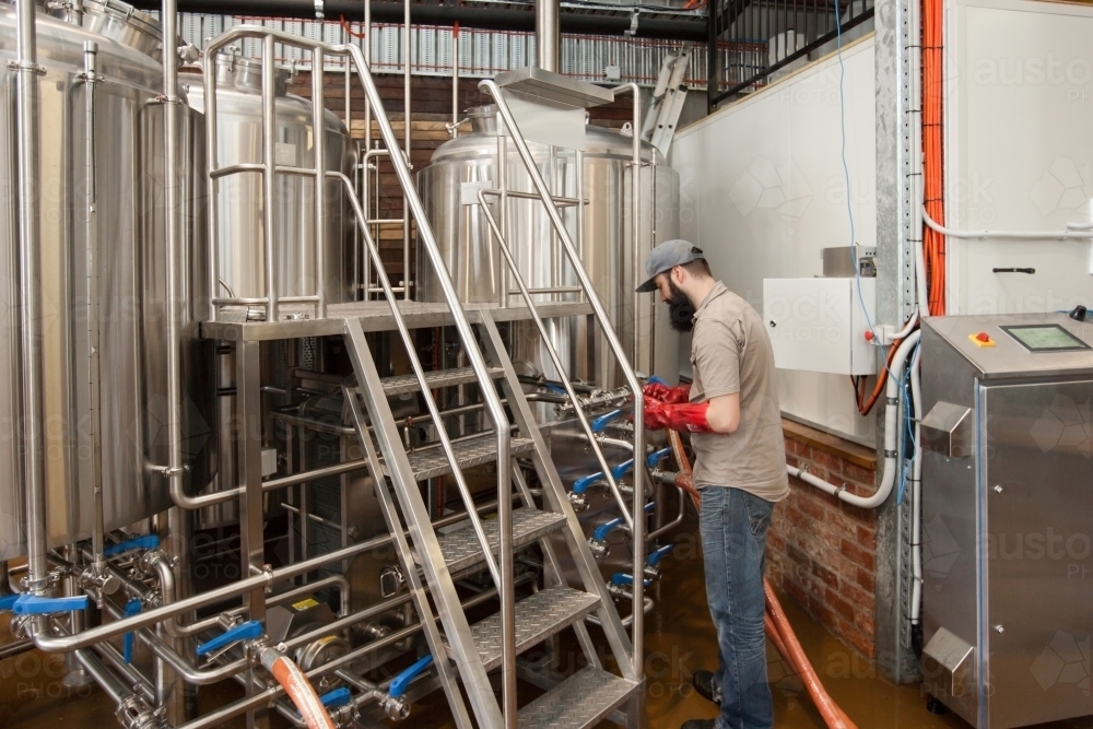 Brewer changing lines at a microbrewery - Australian Stock Image