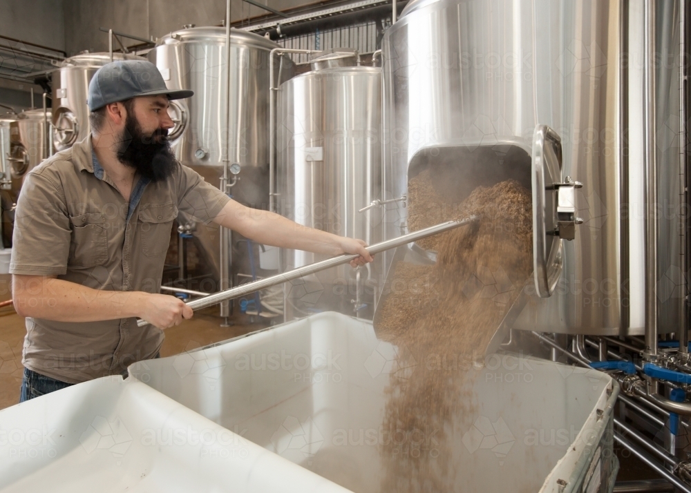 Brewer clearing out waste mash from stainless steel tank - Australian Stock Image