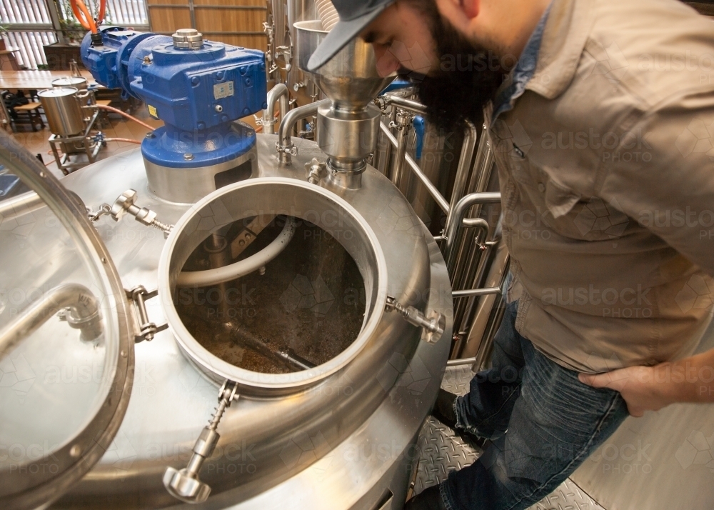 Brewer supervising mash in stainless steel tank - Australian Stock Image