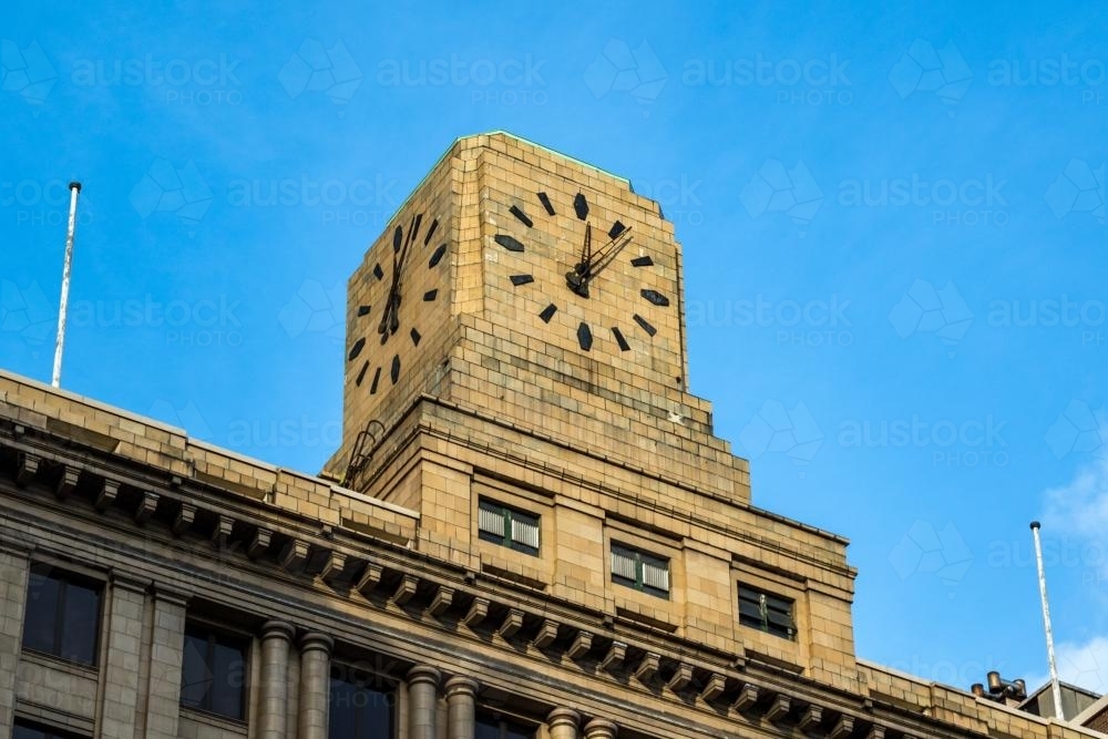 Brick clock on top of building against blue sky - Australian Stock Image