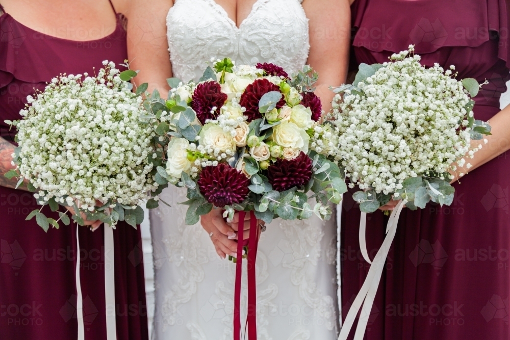 Bride and bridesmaids holding bouquets of baby's-breath flowers - Australian Stock Image