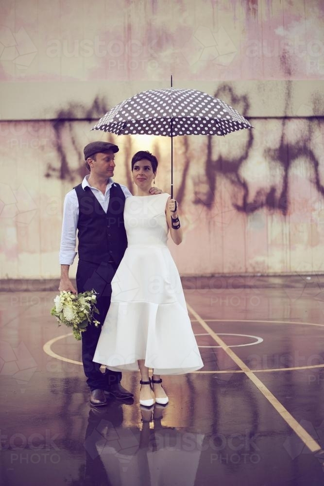 Bride and groom posing under an umbrella - Australian Stock Image
