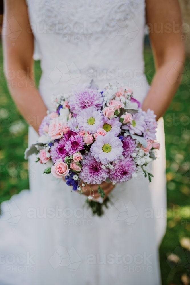 Bride holding a bouquet of pink and purple flowers - Australian Stock Image