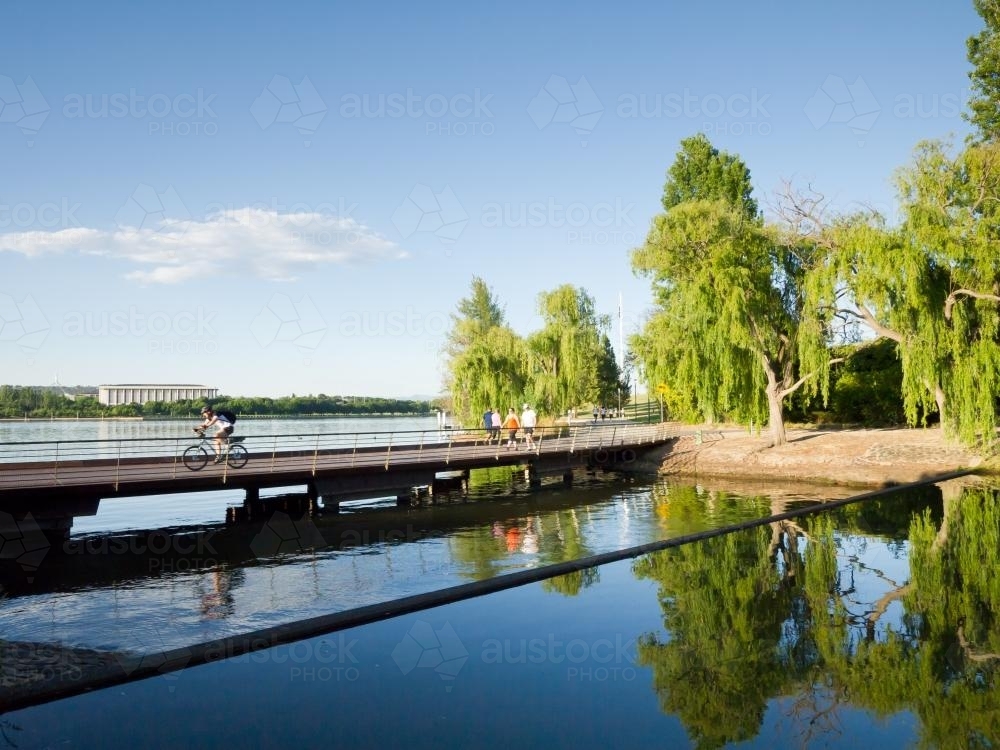 Bridge across water with cyclist and people - Australian Stock Image