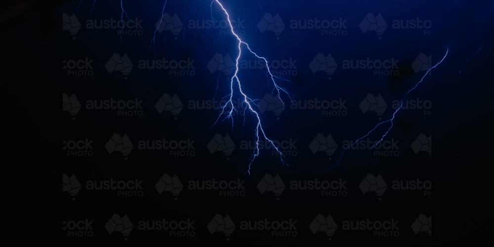 Image of Bright blue lightning strikes illuminate the dark night sky ...