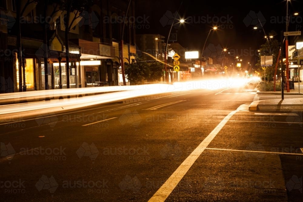 Bright car light trails coming down a street in Singleton at night - Australian Stock Image