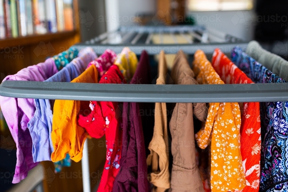 Image of Bright colourful clothes hanging to dry inside on clothes