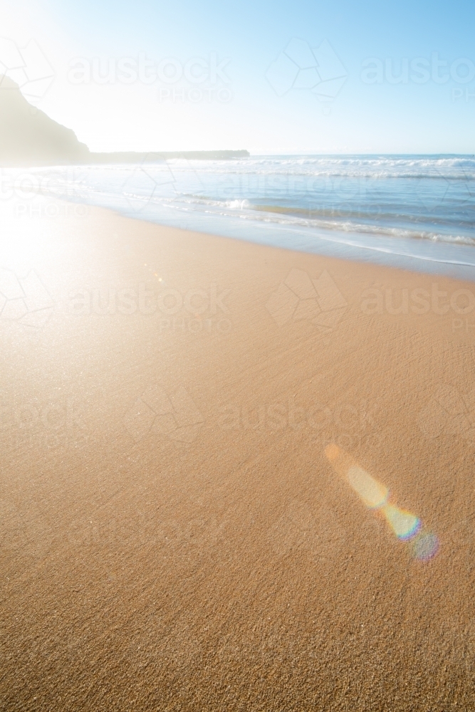 Bright sun flare on untouched empty yellow sandy beach - Australian Stock Image