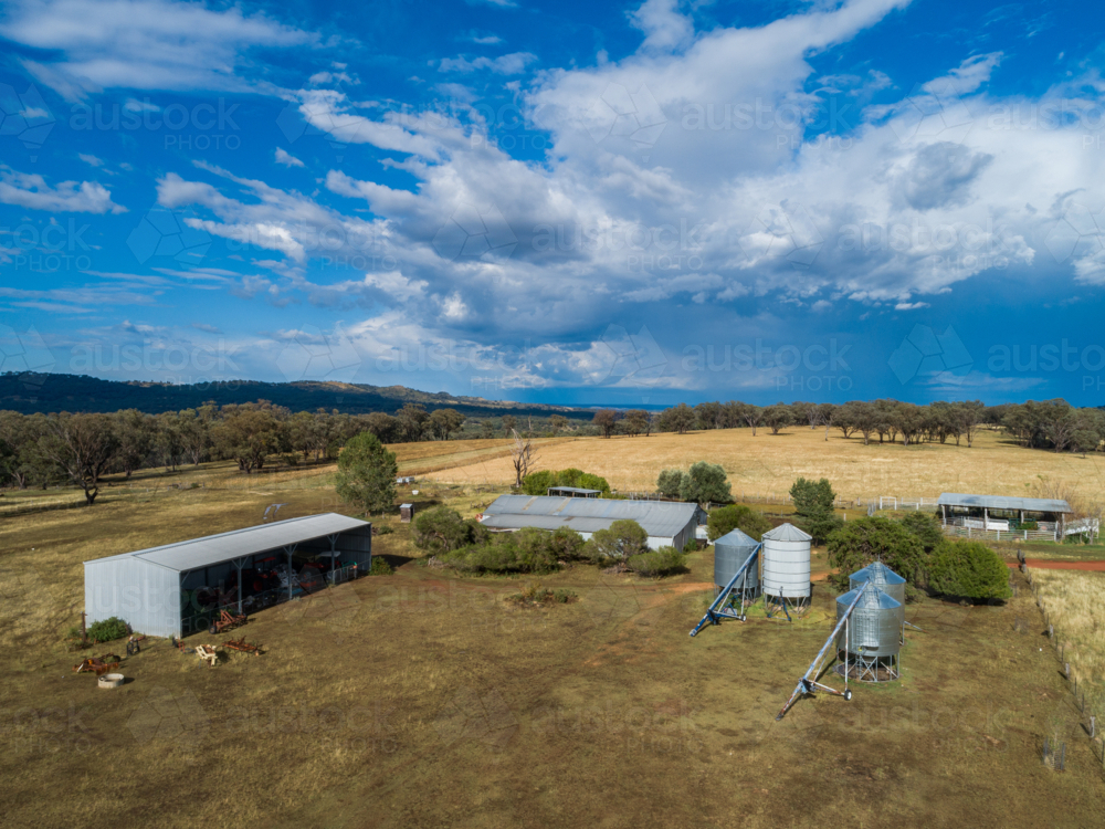 bright sunlit farming landscape of shearing shed silos and farm paddocks in Australia - Australian Stock Image