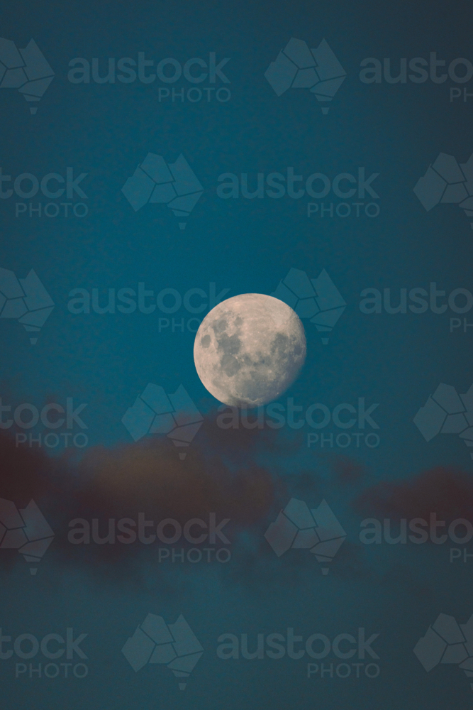 Bright waxing gibbous moon rising above soft evening clouds - Australian Stock Image