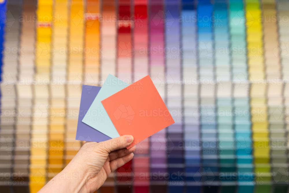 Image of brightly coloured paint samples held up in front of a paint ...
