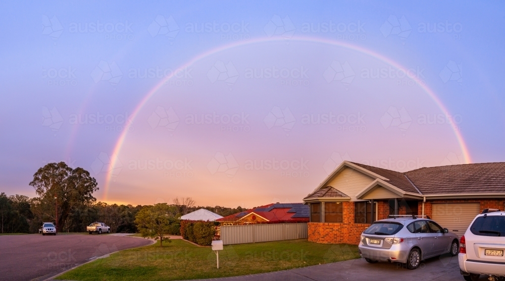 Brightly coloured rainbow curtain over houses at dusk - home concept - Australian Stock Image
