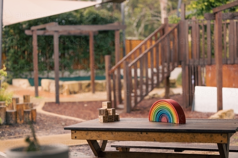Brightly coloured wooden rainbow learning puzzle in nature-based playground environment - Australian Stock Image