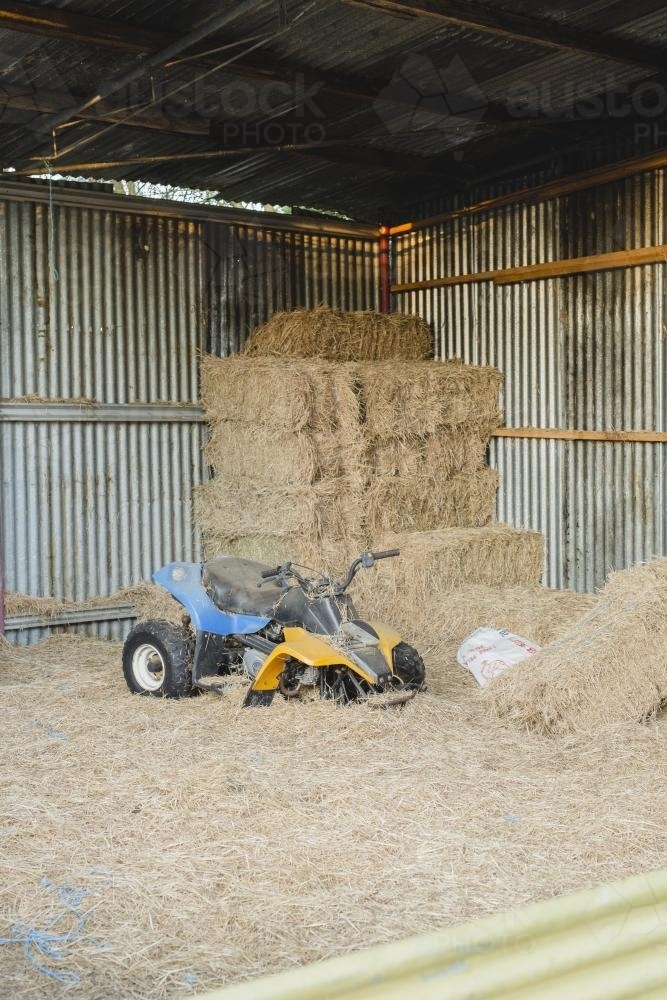 Broken quad bike in hay shed - Australian Stock Image