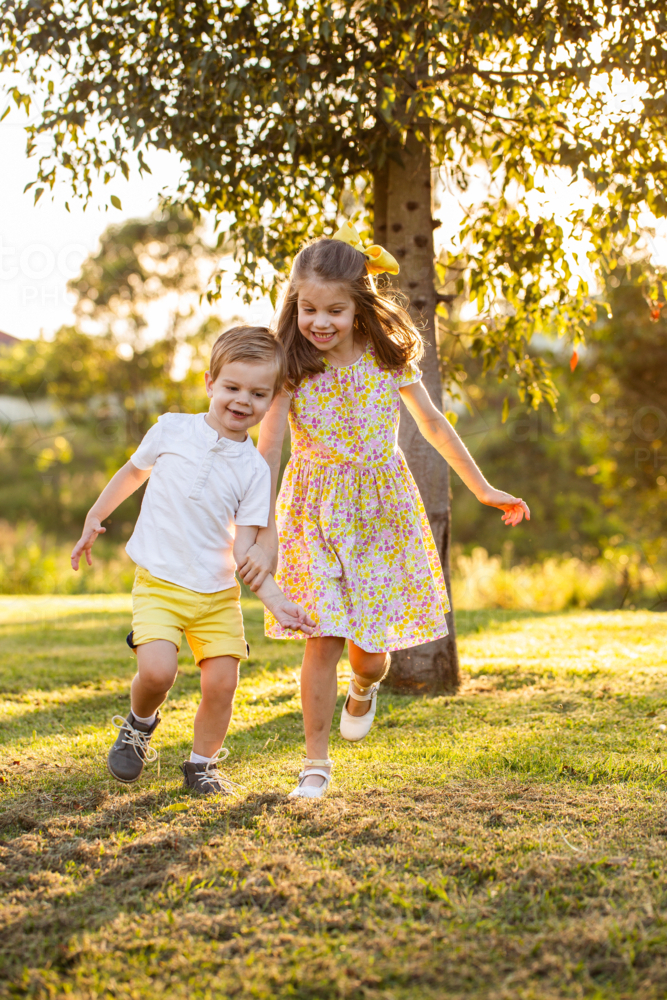 Image of Brother and sister holding hands running together outside at ...
