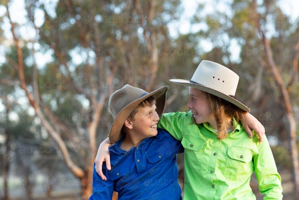 Brother and sister in country setting with arms around each other - Australian Stock Image