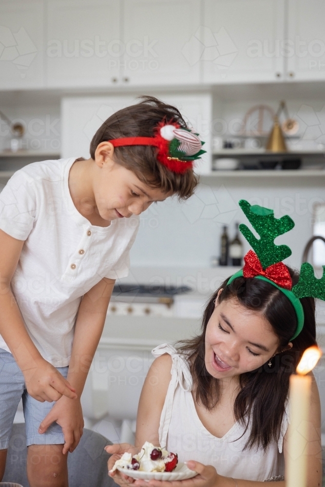 Brother and sister looking at slice of pavlova on plate - Australian Stock Image