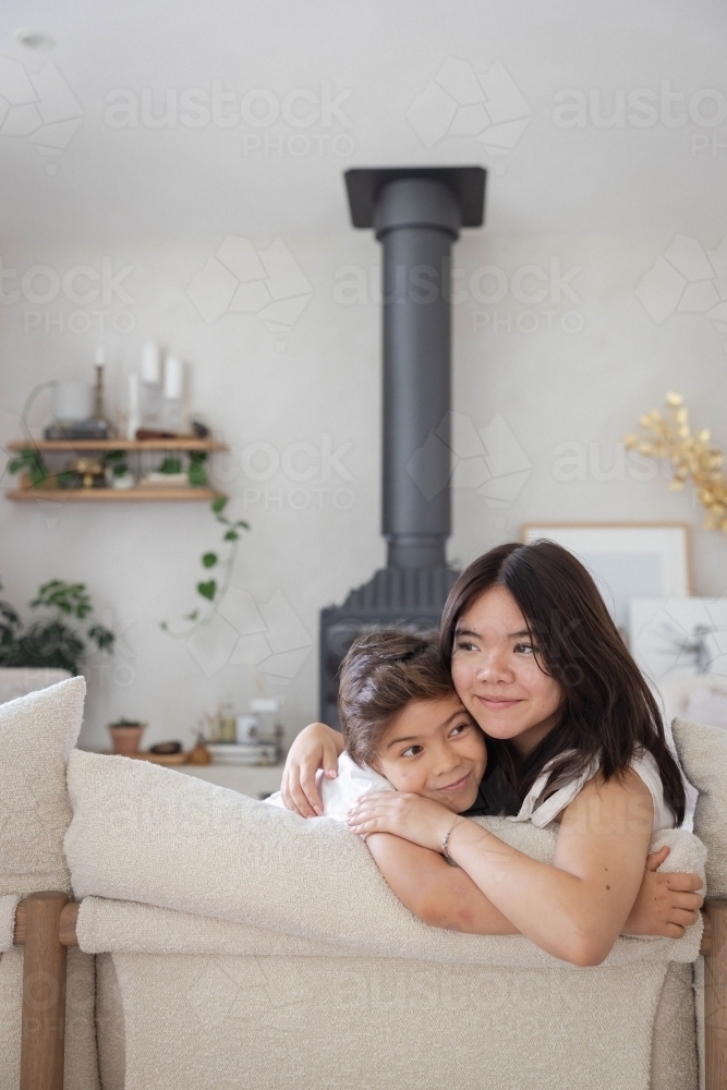 Brother and sister on couch at home together - Australian Stock Image