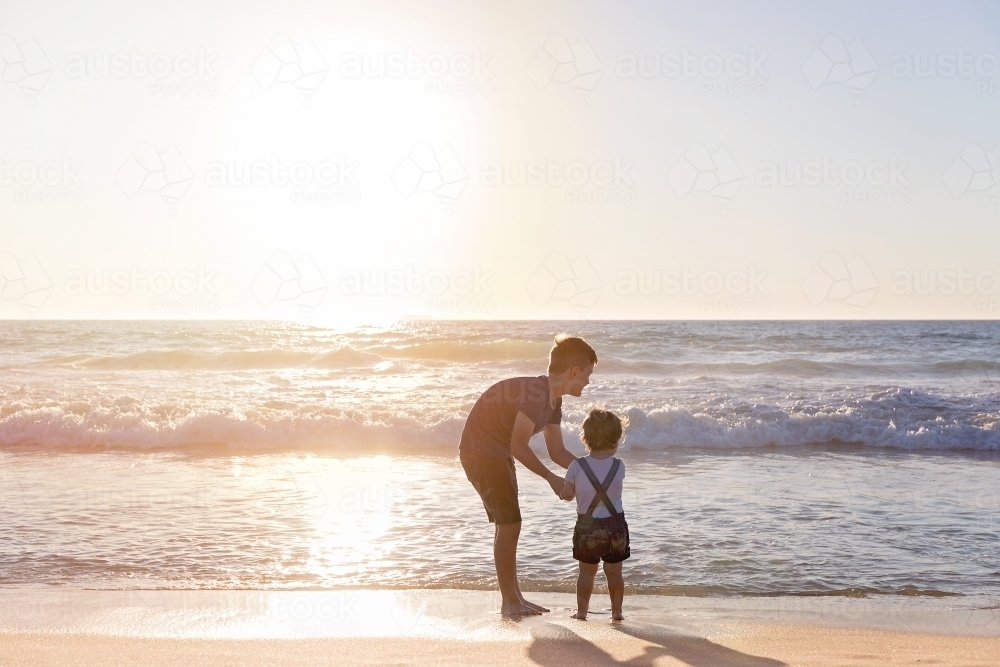 Brother and Sister Playing On The Beach At Sunset Looking At The Ocean - Australian Stock Image