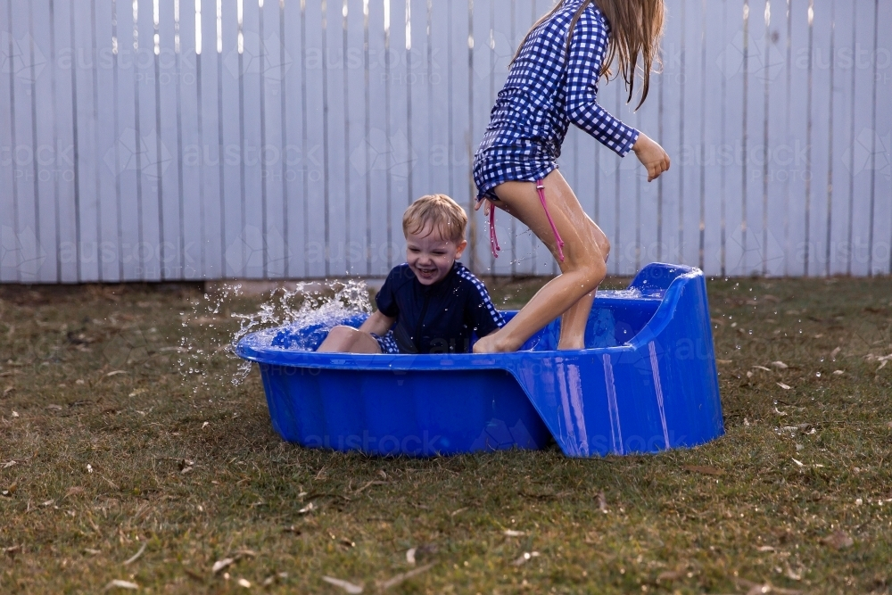 brother and sister playing together in a blue paddle pool - Australian Stock Image
